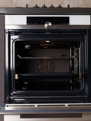 Built-in electric oven with an open door in the interior of the kitchen. Oven with display, convection. Built-in appliances for the kitchen.